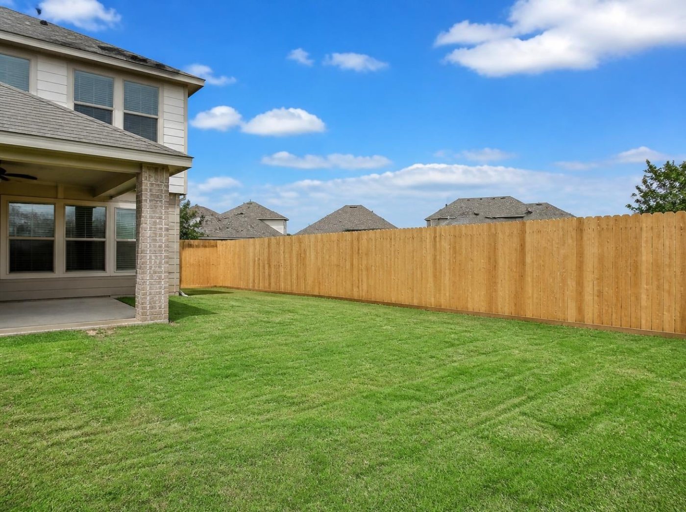 New wood privacy fence along the backyard of a newly built two-story home